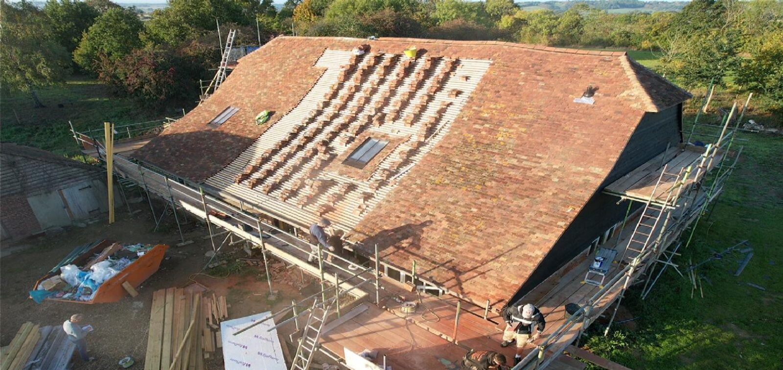 Blended reclaimed peg tiles across a long barn roof